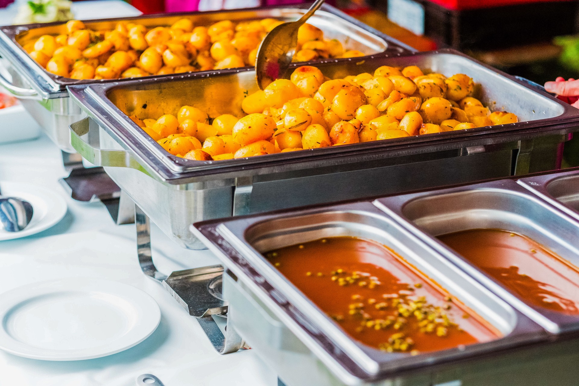 Delicious Buffet Setting with Golden Potatoes and Savory Sauce Ready for Serving at a Party or Event